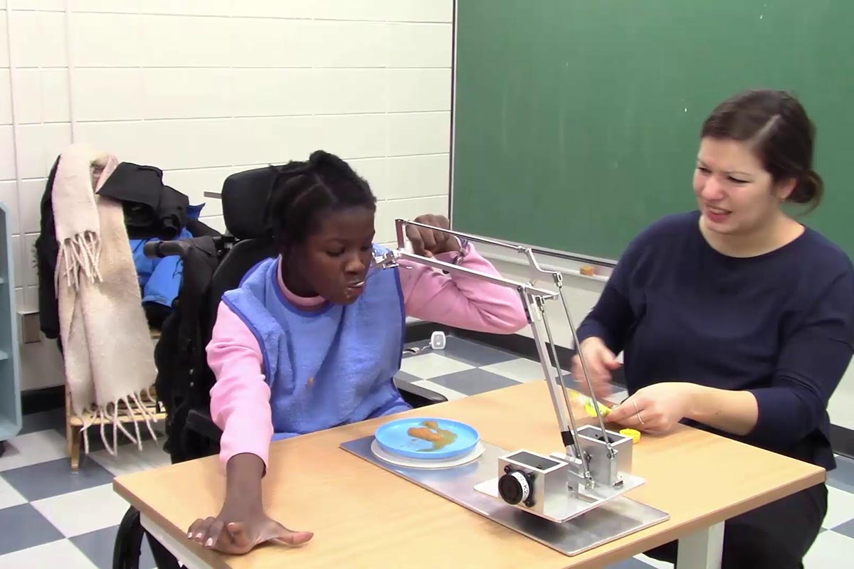 A young girl living with a disability uses a support aid to eat.
