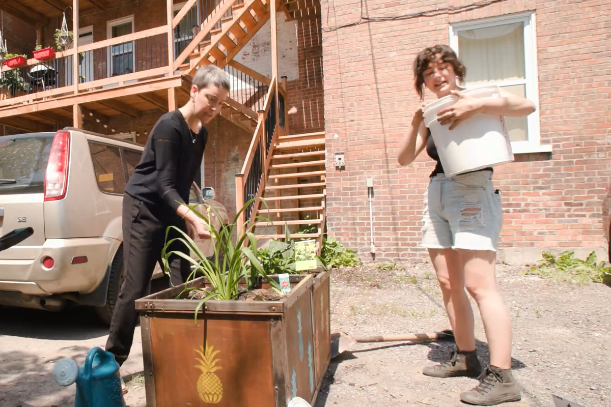 Geneviève Cloutier et une citoyenne verdissent un bac en bois dans une ruelle