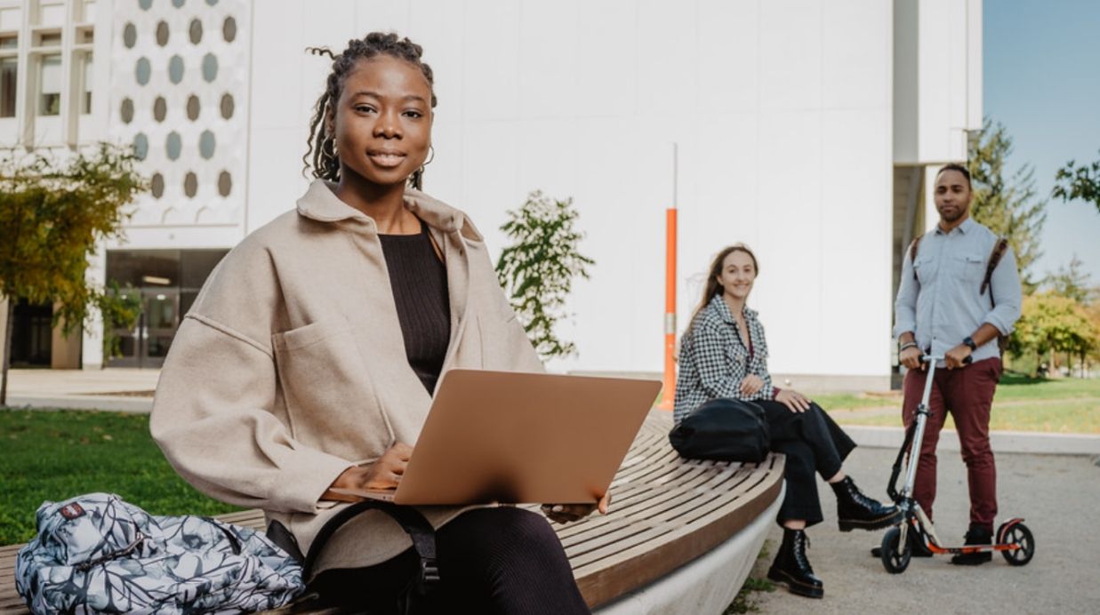étudiante assise sur un banc avec un ordinateur portable sur les genoux