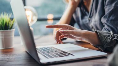 Main pointant un ordinateur portable